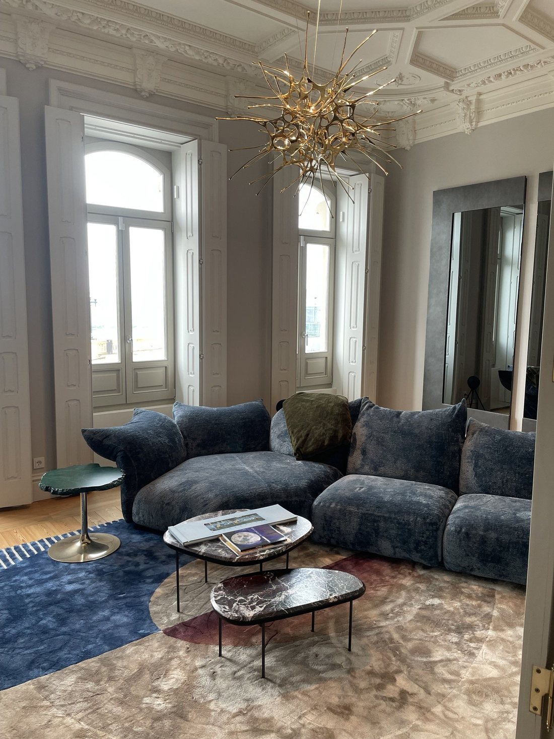 Sala de apartamento de época com tetos em estuque trabalhado e candeeiro escultórico dourado da Terzani