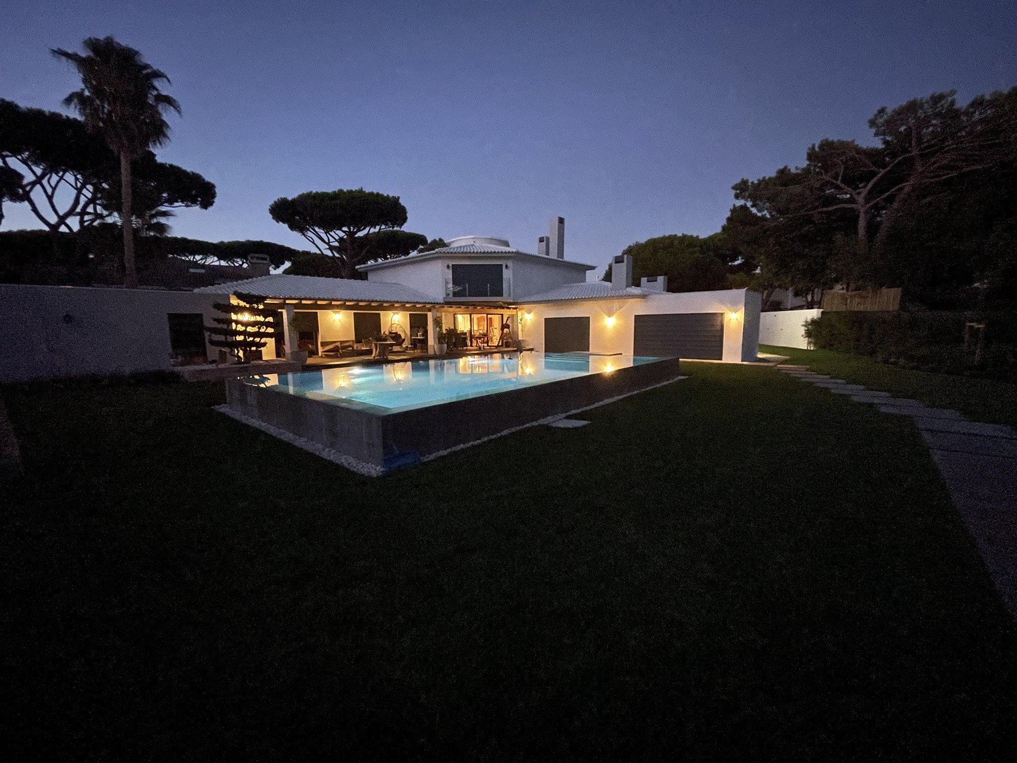 Moradia na Quinta da Marinha ao anoitecer, com iluminação exterior e piscina